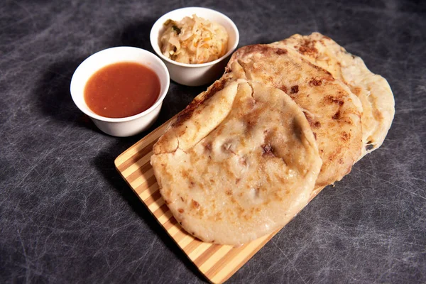 Ahşap bir tahtanın üzerinde siyah mermer bir arka planda el yazısı ve sos olan köpek yavruları.