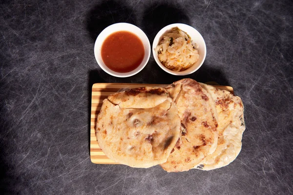 Ahşap bir tahtanın üzerinde siyah mermer bir arka planda el yazısı ve sos olan köpek yavruları.