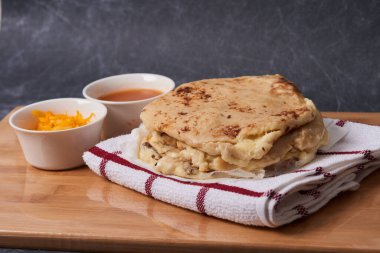 Ahşap bir tahtanın üzerinde siyah mermer bir arka planda el yazısı ve sos olan köpek yavruları.