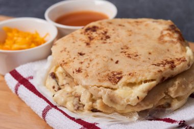 Ahşap bir tahtanın üzerinde siyah mermer bir arka planda el yazısı ve sos olan köpek yavruları.