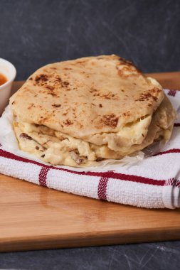 Ahşap bir tahtanın üzerinde siyah mermer bir arka planda el yazısı ve sos olan köpek yavruları.