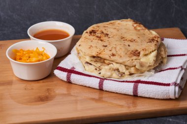 Ahşap bir tahtanın üzerinde siyah mermer bir arka planda el yazısı ve sos olan köpek yavruları.