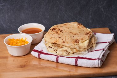 Ahşap bir tahtanın üzerinde siyah mermer bir arka planda el yazısı ve sos olan köpek yavruları.