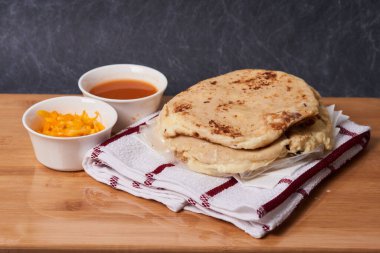 Ahşap bir tahtanın üzerinde siyah mermer bir arka planda el yazısı ve sos olan köpek yavruları.