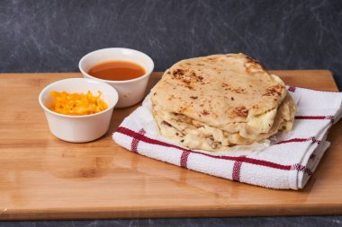 Ahşap bir tahtanın üzerinde siyah mermer bir arka planda el yazısı ve sos olan köpek yavruları.