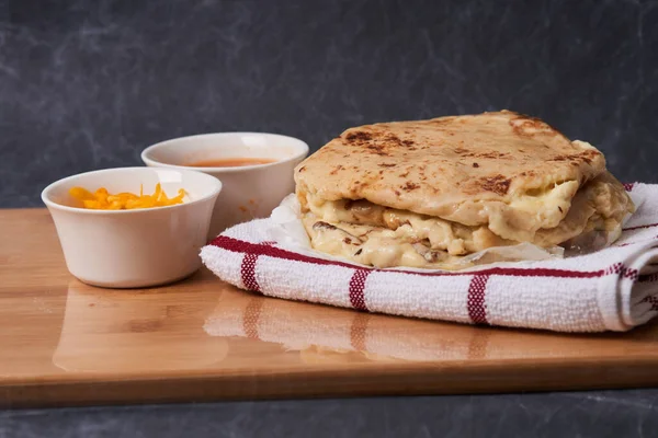 Ahşap bir tahtanın üzerinde siyah mermer bir arka planda el yazısı ve sos olan köpek yavruları.