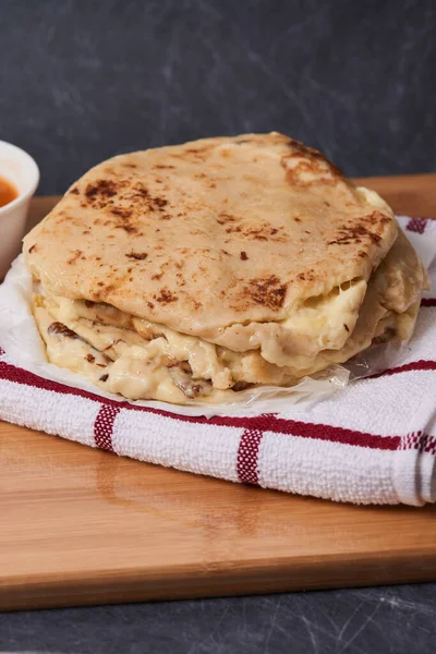 Ahşap bir tahtanın üzerinde siyah mermer bir arka planda el yazısı ve sos olan köpek yavruları.