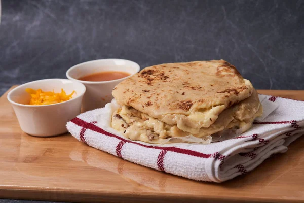 Ahşap bir tahtanın üzerinde siyah mermer bir arka planda el yazısı ve sos olan köpek yavruları.