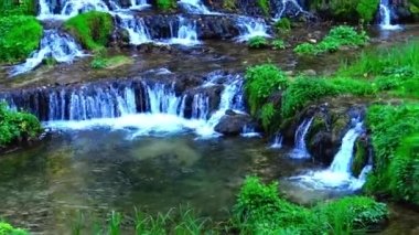 Taze dağ nehri suyu çağlayanlarla dolup taşarken doğal arazide akıyor..