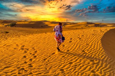 Gün batımında çölde yürüyen bir kadın..