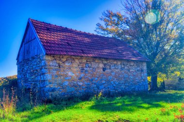 Old stone made house in autumn landscape during sunny day.