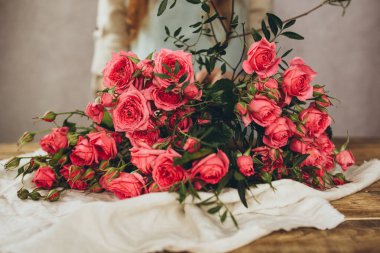 Ahşap bir masanın üzerindeki pembe güllerin yakın plan çekimi..