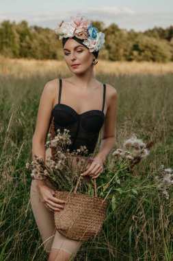 Üstü ve şortlu, şapkalı ve çiçekli kızlar, doğanın arka planına karşı poz veriyorlar. İlk kız sazlığın sapını tutuyor. Elinde sepet olan başka bir kız....