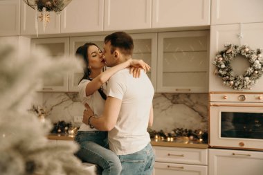 Kot pantolon ve tişört giyen üç kişilik bir aile yeni yıl mekanlarında poz veriyor.