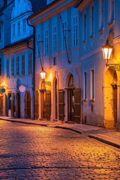 Empty cobble stone street in Prague, Czechia at sunrise with street lights