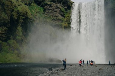 Güney İzlanda 'daki Skogarfoss şelalesinde turistler var. Yüksek kalite fotoğraf