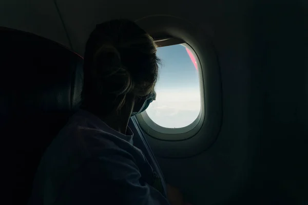 Una Ragazza Maschera Guarda Attraverso Oblò Aereo Foto Alta Qualità — Foto Stock