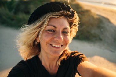 selfie of a traveler on the beach wearing a hat at sunset. High quality photo