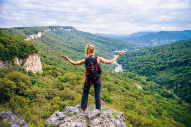 Yüksek dağlardaki kayalıklarda yürüyüş yapan turist kız ve vadinin muhteşem manzarasının tadını çıkarıyor. Yüksek kalite fotoğraf
