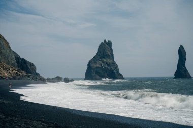 Reynisfjara 'nın kara kumlu plajı ve İzlanda' nın güney kıyısındaki Dyrholaey promontory 'den Reynisfjall Dağı. Yüksek kalite fotoğraf