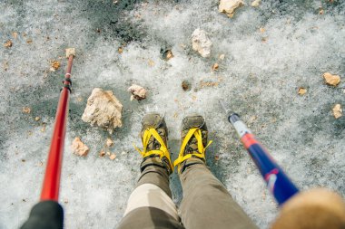 top view of climbers legs in crampons with trekking poles clipart