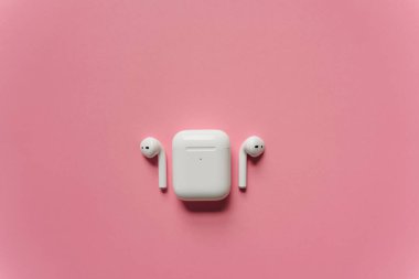 Kablosuz şarj kutusu olan beyaz kulaklıklar. Yeni hava araçları 2019-2020 pembe arka planda. Kadın ve erkek kulaklıkları. Uzayı kopyala - Telefon. Kanada - Mayıs, 2022