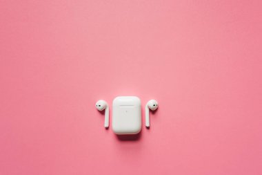 Kablosuz şarj kutusu olan beyaz kulaklıklar. Yeni hava araçları 2019-2020 pembe arka planda. Kadın ve erkek kulaklıkları. Uzayı kopyala - Telefon. Kanada - Mayıs, 2022
