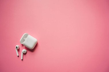 Kablosuz şarj kutusu olan beyaz kulaklıklar. Yeni hava araçları 2019-2020 pembe arka planda. Kadın ve erkek kulaklıkları. Uzayı kopyala - Telefon. Kanada - Mayıs, 2022