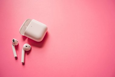 Kablosuz şarj kutusu olan beyaz kulaklıklar. Yeni hava araçları 2019-2020 pembe arka planda. Kadın ve erkek kulaklıkları. Uzayı kopyala - Telefon. Kanada - Mayıs, 2022