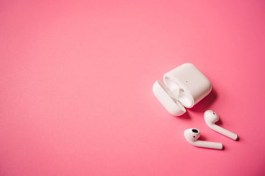 White headphones with wireless charging case. New Airpods 2019-2020 on pink background. Female and male headphones. Copy Space. Phone. canada - may, 2022 clipart