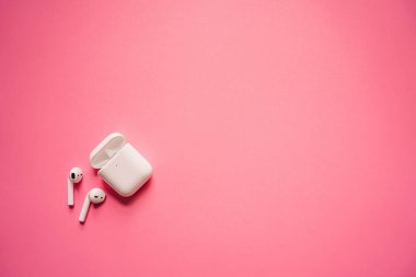 Kablosuz şarj kutusu olan beyaz kulaklıklar. Yeni hava araçları 2019-2020 pembe arka planda. Kadın ve erkek kulaklıkları. Uzayı kopyala - Telefon. Kanada - Mayıs, 2022