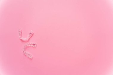 Diş telleri ya da pembe arka planda görünmez diş telleri. Yüksek kalite fotoğraf