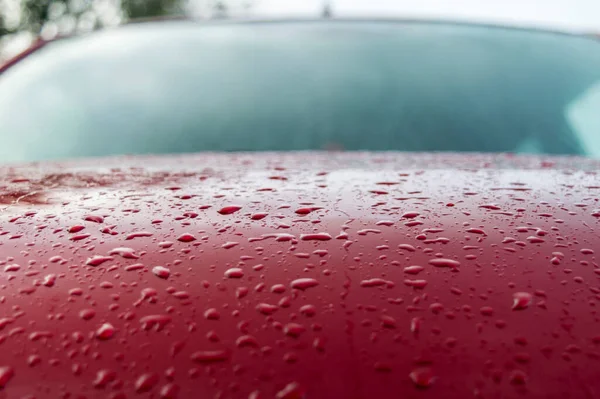 Splashes and water drops on a red car surface forming a beautiful texture pattern background.