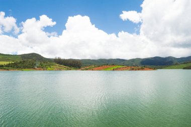 Manzaralı Ooty Gölü, mavi ve beyaz gökyüzü, suda görülebilir yansıma, doğanın her yerdeki yeşillik armağanı Ooty 'nin güzelliğini açıklayabilmenin tek yolu..