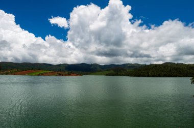 Manzaralı Ooty Gölü, mavi ve beyaz gökyüzü, suda görülebilir yansıma, doğanın her yerdeki yeşillik armağanı Ooty 'nin güzelliğini açıklayabilmenin tek yolu..