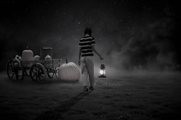 A black and white picture of a little girl walking home with a lantern on Halloween night alone.