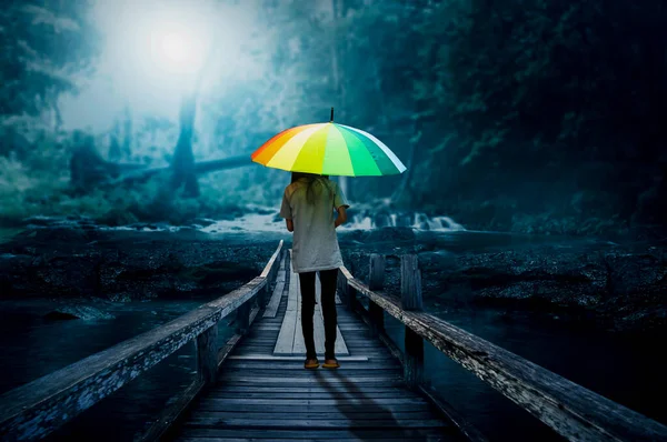 寂寞的夜晚 一个拿着雨伞的小女孩走过森林里的桥 — 图库照片