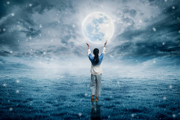 The little girl stood holding the moon beautifully on the full moon night.