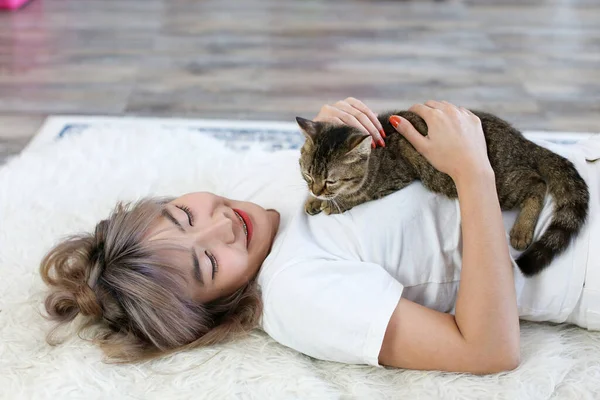 Asian women are playing with cats in the living room.