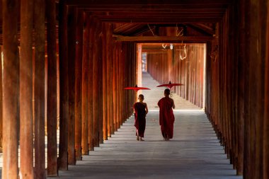 26 Ocak 2021 'de Myanmar' da Bagan 'da tahta yolu olan bir tapınakta şemsiye tutan bir keşiş yürür..
