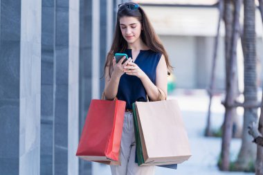 Alışverişin tadını çıkarıyorum. Güzel bir kadın kese kağıdıyla alışveriş yapmayı ve şehirde cep telefonu kullanmayı sever..