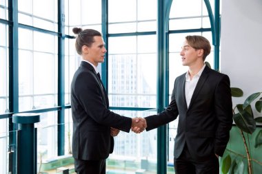 İş adamları başarılı bir ortaklık takımı olmaktan mutluluk duyar. Gülümseyen işadamı el sıkışıyor.