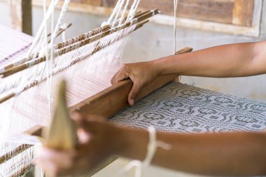 Traditional Isan Thai cotton weaving. old woman hand weaving cotton in traditional way at manual loom. Loei, Thailand.