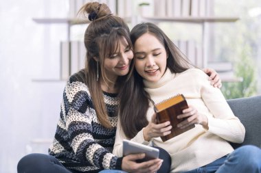 Kalimba oynayan ve oturma odasındaki kanepede tablet kullanan genç bir kadın.. 