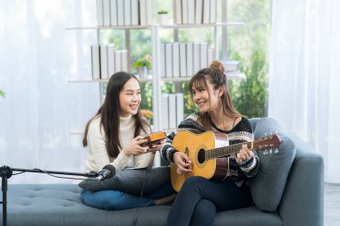 Oturma odasında gitar ve kalimba çalan iki genç bayan.. 