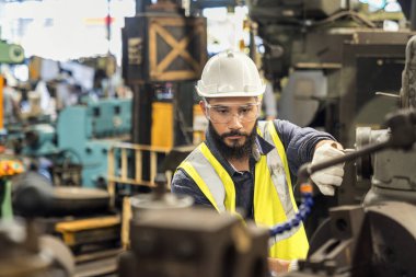 Teknisyen adam çelik fabrikasında çalışıyor. Güvenlik kasklı bir işçi çelik makinesinde çalışıyor..