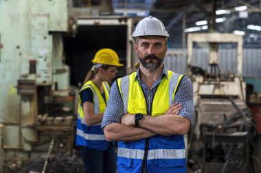 Mühendisler ve yetenekli teknisyenler makineleri koruyor. Mühendisler endüstriyel alanda çalışıyor ve makineleri tamir ediyorlar. İşçi, fabrikanın yakınında el ele tutuşmuş şekilde dururken,.