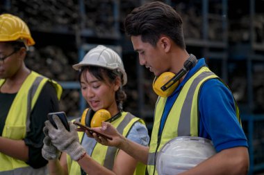 Mühendisler veya teknisyenler depo ve fabrikalardaki otomobil parçalarını inceliyor. Cep telefonu kullanan fabrika teknisyeni.