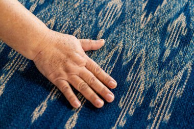 Yaşlı bir kadın pamuktan yapılmış ipliği inceliyor. Yerel usta Sakon Nakhon bölgesinin orjinal Indigo Cotton Weaver 'ıdır..