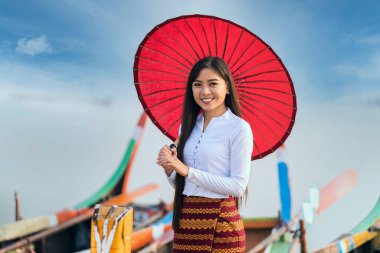 Mandalay, Myanmar 'daki U-bein köprüsünde duran ve elinde kırmızı şemsiye tutan genç bir Burmalı kadın. Metin için boşluk.